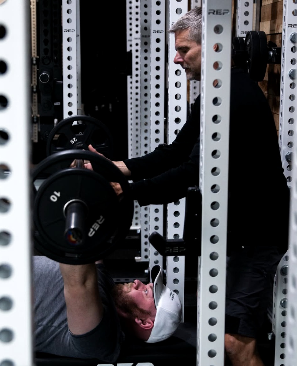 Personal trainer spotting a bench press during strength training